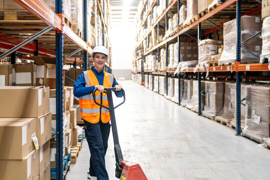 Woman in safety vest and hard hat working at a logistics distribution center, moving goods efficiently