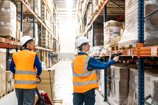 Two workers in safety vests and hard hats operating equipment and scanning barcodes in a modern fulfillment center