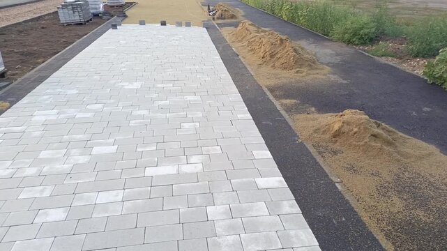 Installation of interlocking concrete pavers on construction site, road paving, landscaping and urban infrastructure.
