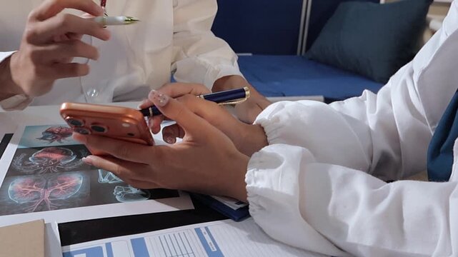 Two asian women doctors discuss meeting doctor's office medical clinic looking x-ray film consulting patient disease. Asian medical lab young women talking together discussing healthcare teamwork