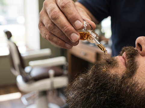 Barber applying grooming oil to a thick male beard
