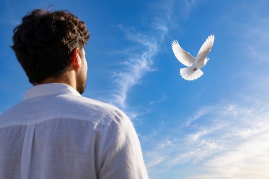 Man watches white dove fly in clear blue sky