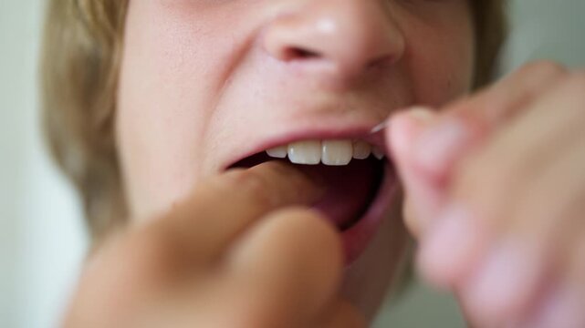 Independent teenage boy flossing his teeth in front of a bathroom mirror, taking responsibility for his personal hygiene and developing healthy dental care habits as part of his daily routine.