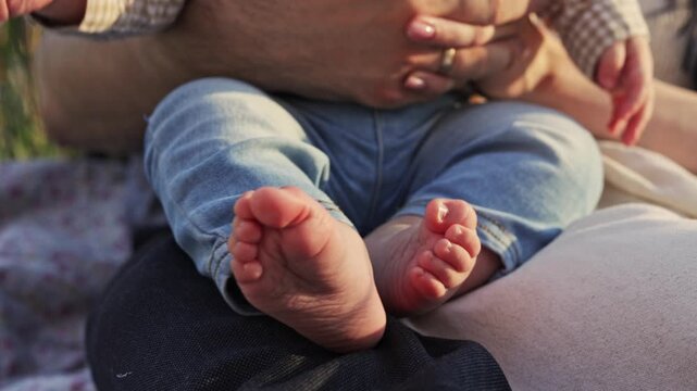 Close-up of a baby's tiny feet being held by parents outdoors
