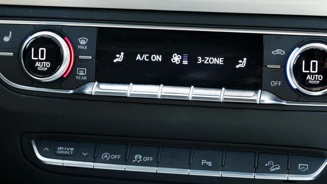 Modern car interior showing advanced digital climate control panel. Display indicates air conditioning system active, multi-zone temperature regulation