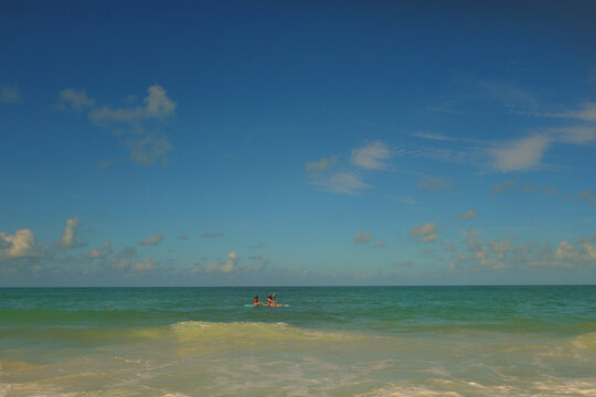 Two teen girlsp on a paddleboard in the open ocean