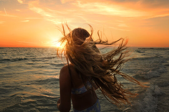 Girl's hair blows in the wind at sunset