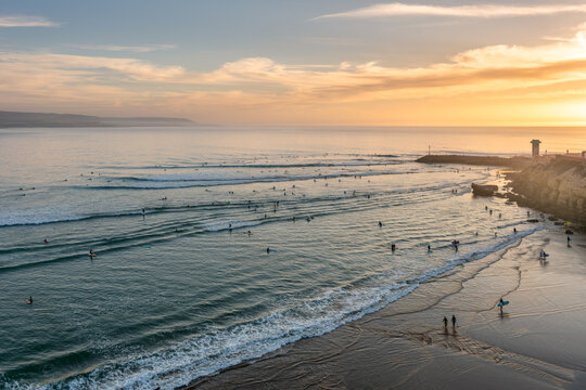 Surfers catching waves in Imsouane bay at sunset in Morocco