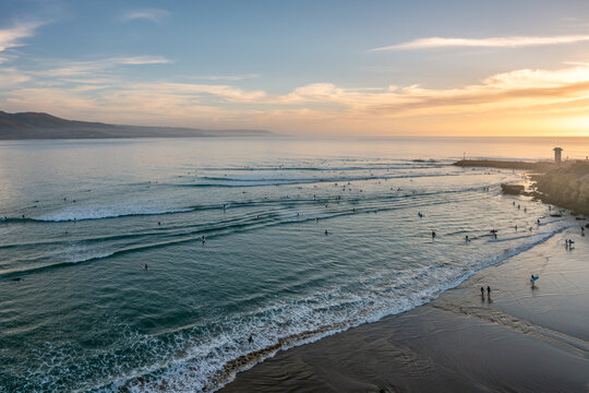 Surfers catching waves in Imsouane bay at sunset in Morocco