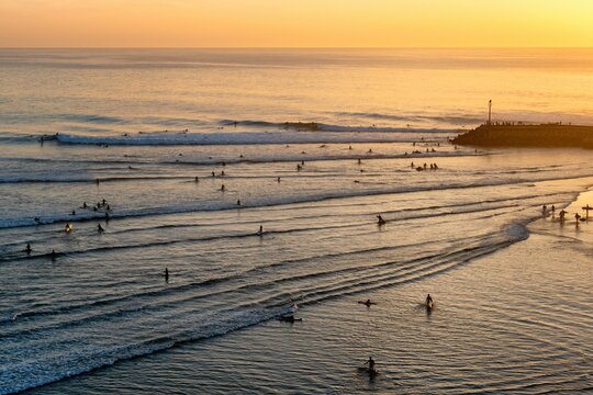 Surfers catching waves in the sea with golden hour sunset in Imsouane