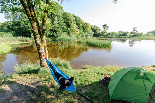 Sport girl lying on hammock on meadow near lake