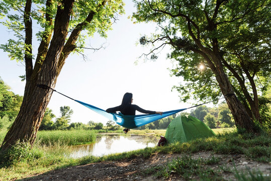 Sport girl lying on hammock on meadow near lake
