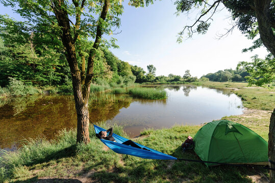 Sport girl lying on hammock on meadow near lake