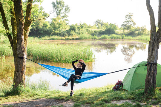Sport girl lying on hammock on meadow near lake