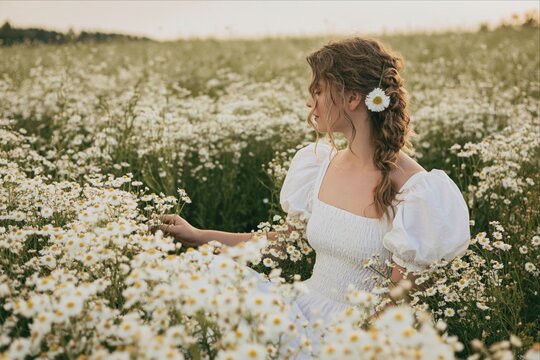 Young woman in white dress in a field of daisies