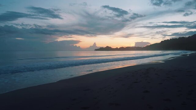 A serene tropical beach at sunset with soft waves rolling onto the sand under a dramatic cloudy sky