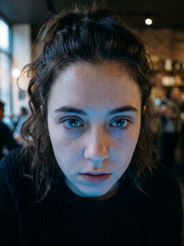 Young Woman Staring Intently at a Screen with Blue Light Reflection.