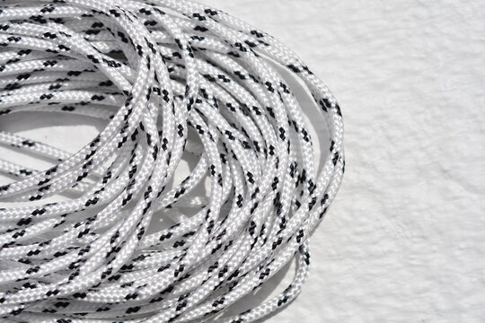 Close up view of a coiled white synthetic rope with black patterns on a bright surface