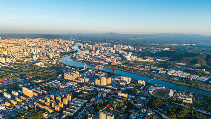 Fototapeta premium Xinyang city panoramic view with river flowing through urban landscape at golden hour