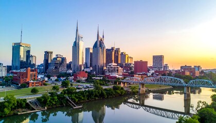 Obraz premium Aerial view of a city skyline at sunset, with tall buildings silhouetted against a golden sky and a river below