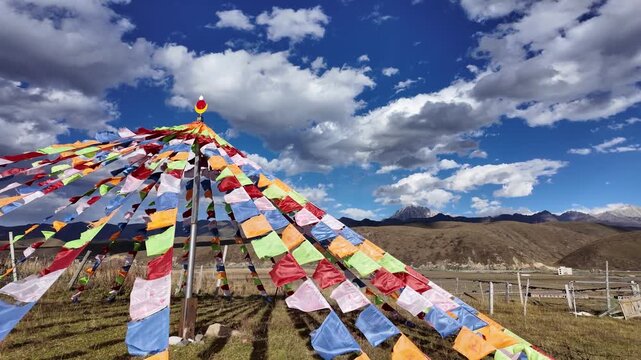 Colorful tibetan buddhist prayer flags fluttering in the wind against a dramatic mountain landscape and blue sky