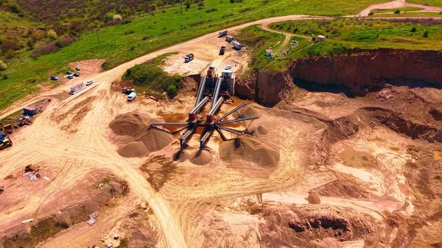 Aerial view of conveyor belts sorting crushed stone into piles at quarry. Overhead view shows conveyor systems distributing processed gravel into conical stockpiles on tan ground.
