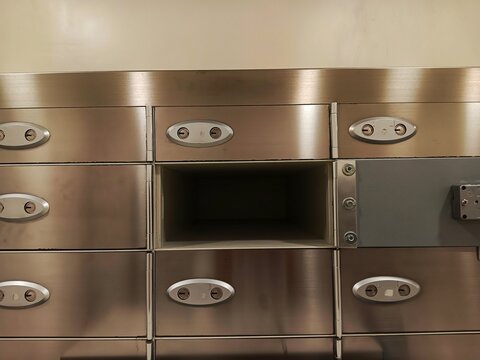 Open empty safety deposit box inside a secure bank vault with stainless steel metal lockers.