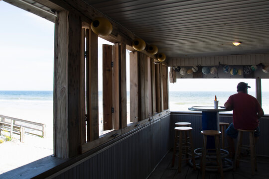 Rear view of man relaxing in seaside bar