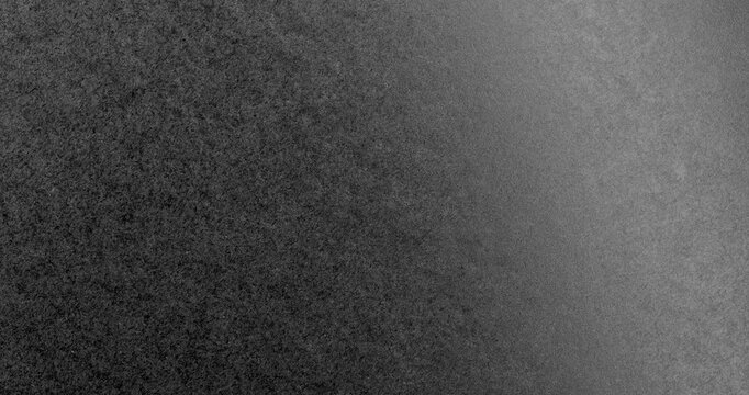 Surface of black paper, slowly rotating. Soft illumination sweeps over a grainy monochrome texture.