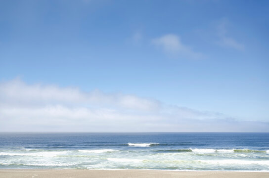 White clouds and blue sky above beach and calm ocean