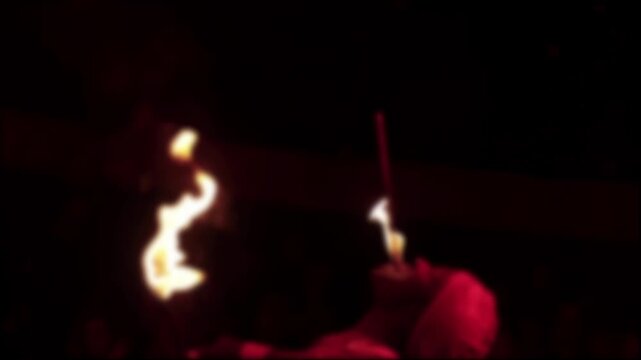 Blurred capture of dynamic fire performance by artist during night circus event, featuring intense fire breathing and skillful torch manipulation, slow motion, blurry