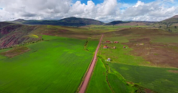 Drone establishing overview above rural fields and mountain valley in Maras district, Peru, aerial of road splitting landscape