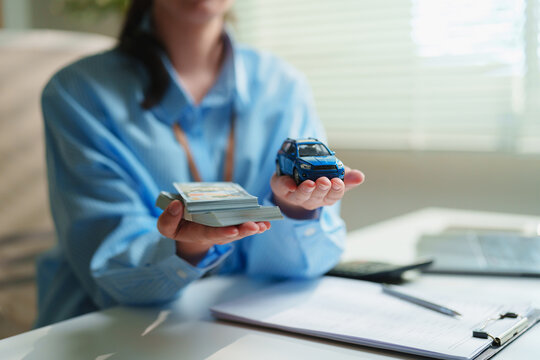 Financial advisor presents cash and a model car, auto financing, vehicle loans, car insurance, leasing, and automotive financial planning for consumers and businesses