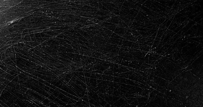 Rotating Scratched Black Surface. A densely scratched dark surface rotates smoothly under directional light, revealing intersecting scuffs and fine abrasion marks. Suitable for grunge backgrounds.