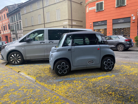 Citroen Ami electric microcar parked on a city street with yellow petals