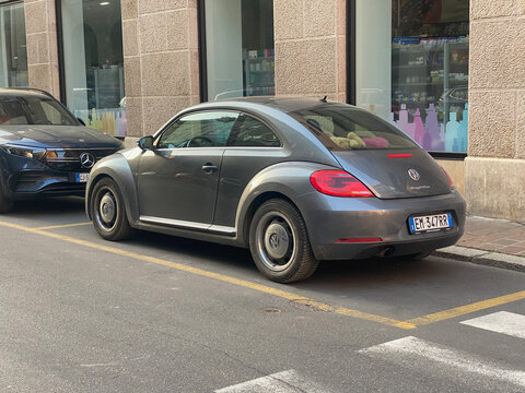 Classic Volkswagen Beetle parked on a city street next to a modern car