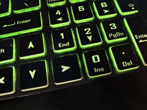 Macro view of illuminated green numeric keypad section on computer keyboard with keyboard, hardware