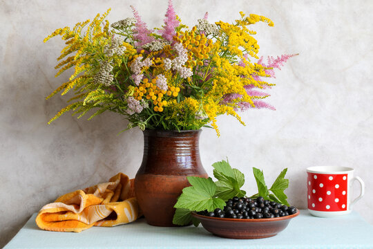 Wildflower bouquet with tansy yarrow goldenrod astilbe and black currants in rustic ceramic vase