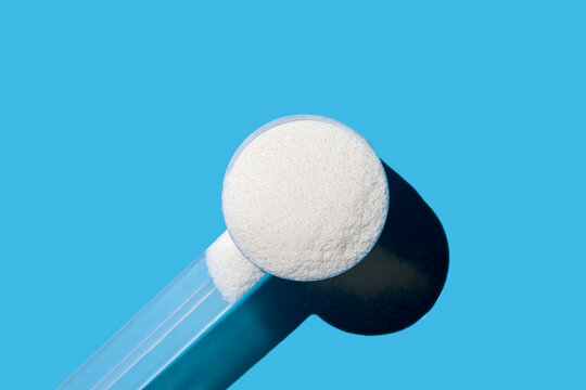 Scoop of collagen powder on blue background