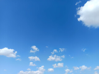 Bright blue sky with scattered fluffy white cumulus clouds on a sunny day, creating a clean natural background with ample copy space for weather, travel, summer, and nature themes. © Pratama