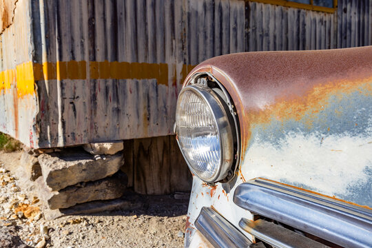 Close-up of abandoned car next to sheet metal building