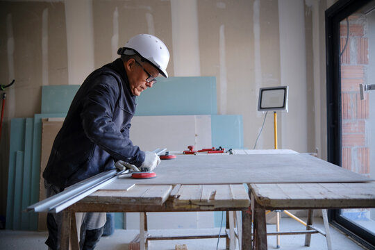 Construction worker with sheetrock on workbench at site