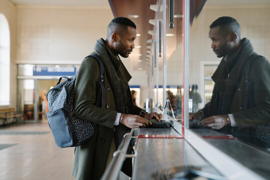 Stylish man buying ticket in train station