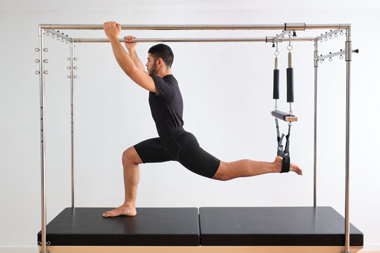 Mid adult male athlete practicing pilates on trapeze table in exercise room