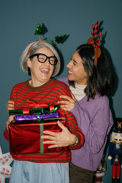Mother and daughter hold Christmas gifts and laugh together