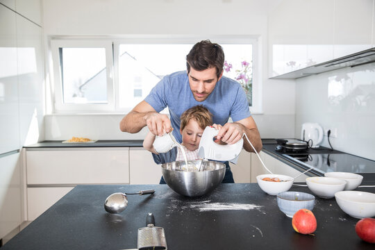 Father and son preparing waffle dough in kitchen