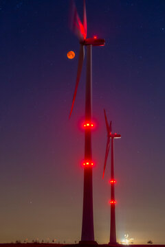 Wind wheels in front of blood moon at night