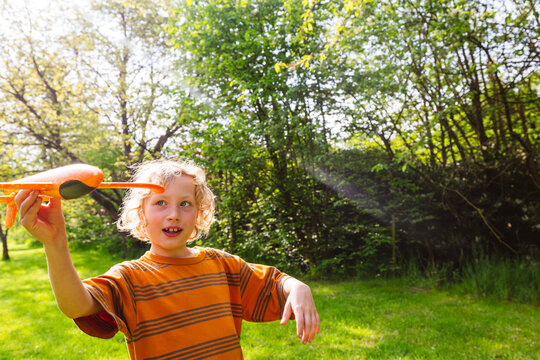 Happy blond boy playing with airplane toy