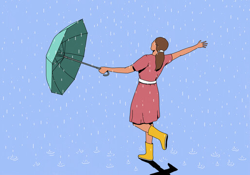Carefree woman lowering umbrella and enjoying rain against blue background