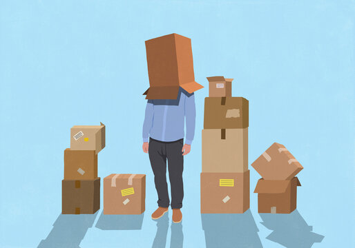 Man surrounded by moving boxes standing with cardboard box covering head against blue background